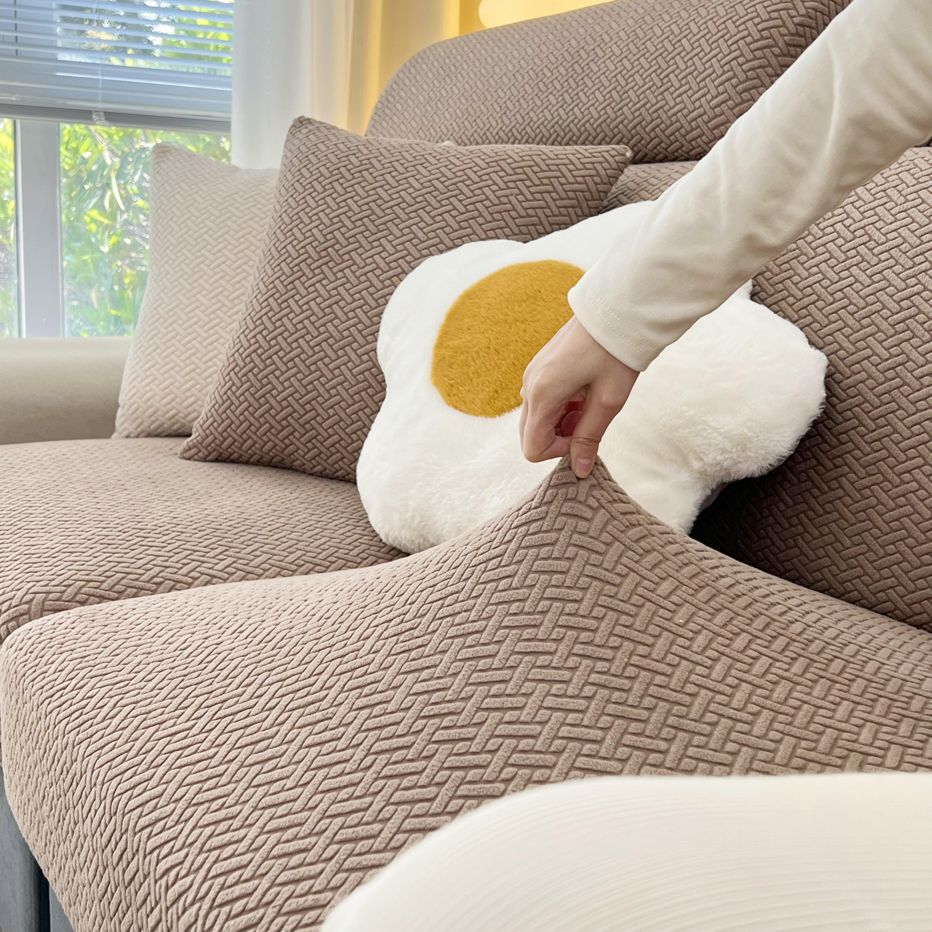Stretchy FancySofas Classic bankhoes in de kleur Desert Khaki, toont elasticiteit en pasvorm door de stof omhoog te trekken.